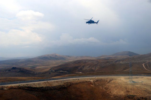 A helicopter flies over the construction of a modular wall across the Turkey-Iran borderline in Van province, Eastern Turkey